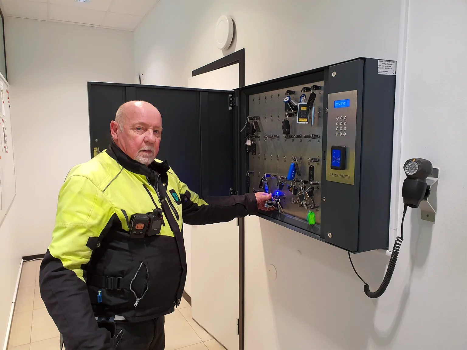 Vakt i gul jacka använder Brightec Securitys digitala nyckelskåp med alkotest